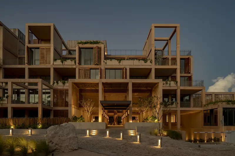 Edificio terminado en Playa del Carmen al atardecer, con la entrada iluminada