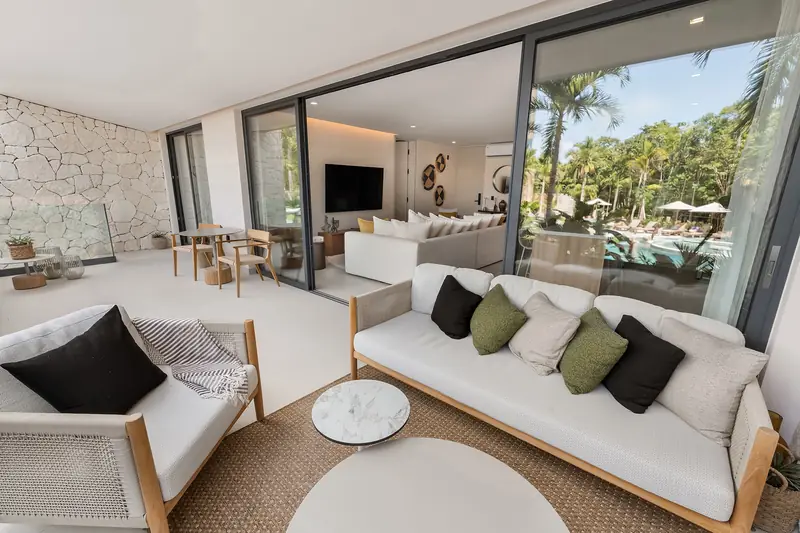 Sala y terraza de un departamento amueblado con vista a la vegetación